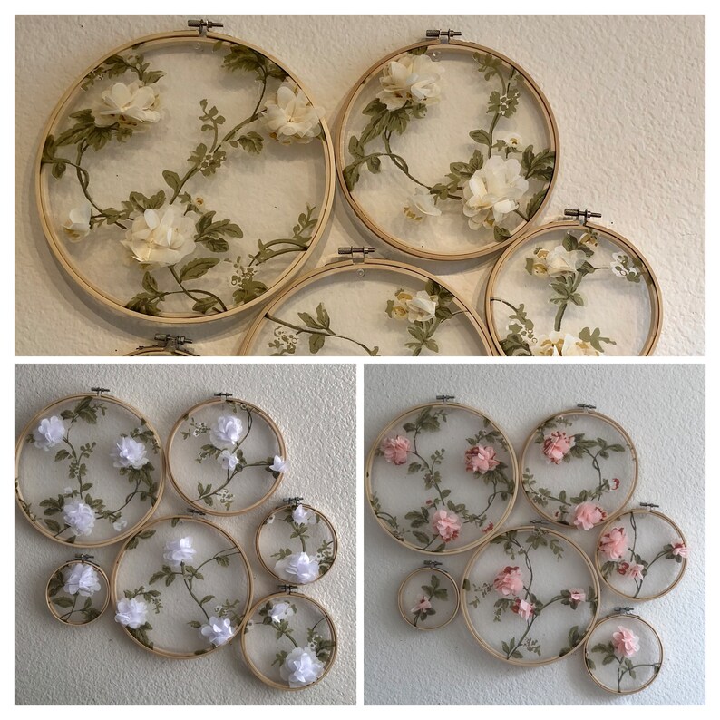May include: A set of eight embroidery hoops with floral designs. The hoops are made of wood and have a natural finish. The designs are made with white and pink fabric flowers and green leaves.