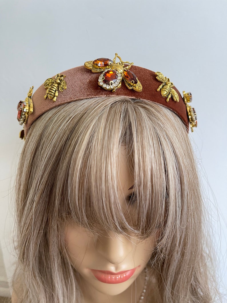May include: A brown velvet headband with gold bee embellishments and sparkling rhinestones.