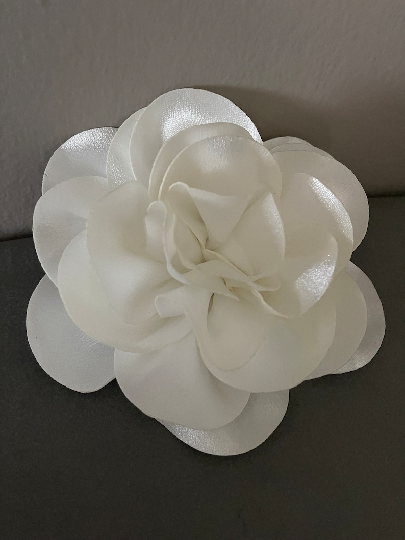 May include: A white satin flower with multiple layers of petals.