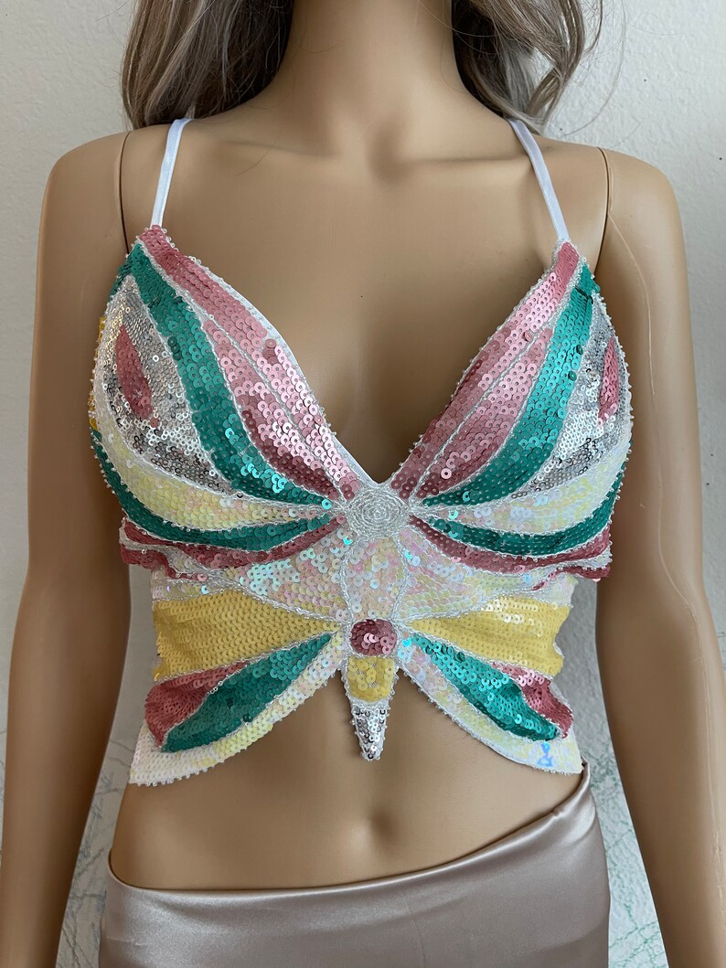 Puede incluir: Un top corto de lentejuelas con un dise&ntilde;o de mariposa en tonos rosa, verde, amarillo y blanco.