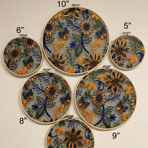 May include: A set of 6 embroidery hoops with floral designs in shades of yellow, blue, and green. The hoops are 5", 6", 7", 8", 9", and 10" in diameter.