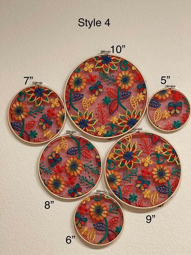 May include: Set of six embroidery hoops with floral designs in shades of red, yellow, green, and blue on a pink background. The hoops are 5, 6, 7, 8, 9, and 10 inches in diameter.