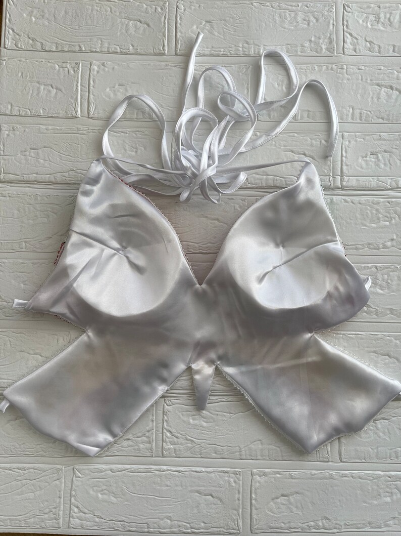 Puede incluir: Top halter blanco de sat&eacute;n con un dise&ntilde;o en forma de mariposa. El top tiene la espalda baja y tirantes ajustables.