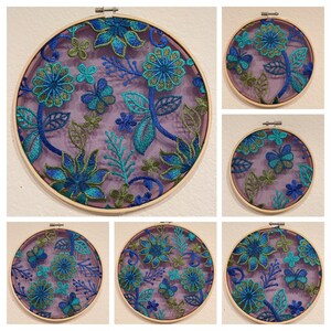 May include: Set of six embroidery hoops with floral designs. The hoops are made of wood and have a natural finish. The embroidery designs feature blue and green flowers on a purple background.