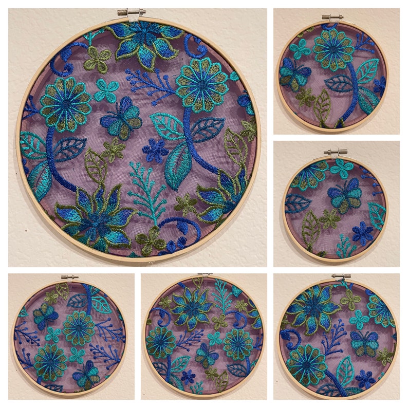 May include: Set of six embroidery hoops with floral designs. The hoops are made of wood and have a natural finish. The embroidery designs feature blue and green flowers on a purple background.