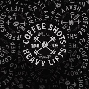Könnte beinhalten: Runder, schwarz-weißer Aufnäher mit dem Text "COFFEE SHOTS HEAVY LIFTS" in einem kreisförmigen Design. Der Aufnäher enthält eine Kaffeebohne und eine Hantel-Grafik, mit den Wörtern "Caffeine" und "Lifestyle".