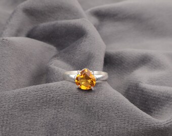 May include: A silver ring with a large, round, orange gemstone set in a prong setting.