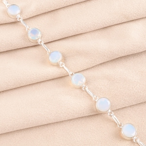 May include: A silver chain bracelet with white opal gemstones. The bracelet has a delicate design and is perfect for everyday wear.