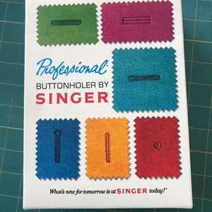 May include: A white box with a colorful illustration of different buttonhole stitches. The text on the box reads "Professional Buttonholer by SINGER. What's new for tomorrow is at SINGER today!"