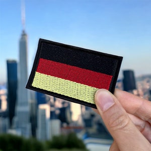 May include: An embroidered patch of the German flag, featuring black, red and yellow colours.