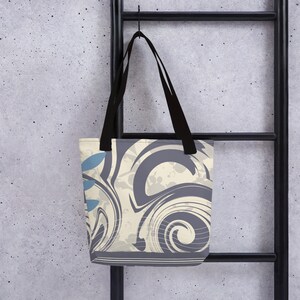May include: A tote bag with black straps and a cream and grey abstract design. The design features swirls and a blue leaf pattern.