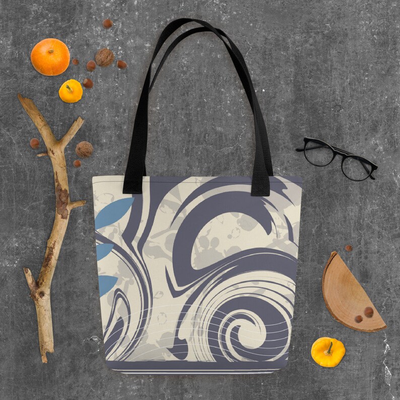 May include: A tote bag with black straps and a cream and grey abstract swirl pattern. The pattern includes blue leaf shapes.