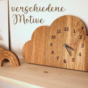 May include: Wooden cloud-shaped clock with black numbers and hands. The clock is on a wooden shelf with two wooden rainbow decorations.