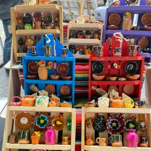 May include: A set of miniature wooden shelves with colorful painted pottery and ceramic items. The shelves are decorated with flowers and have a rustic, handmade look.