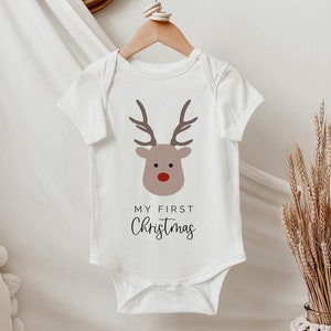 May include: White baby onesie with a red-nosed reindeer graphic and the text "My First Christmas".