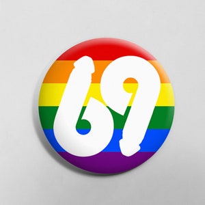 May include: A round button with a rainbow design and the number 69 in white.