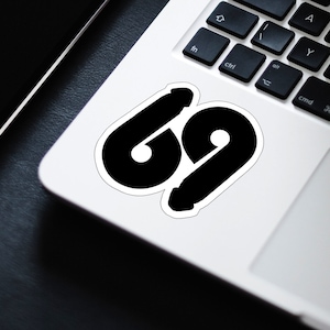 May include: A black and white sticker with the number 69 on a white laptop.
