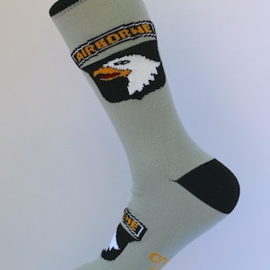 May include: Gray crew sock with black heel and toe, featuring an "AIRBORNE" patch with a white eagle head and yellow beak. The sock has a black cuff and a small logo near the toe.