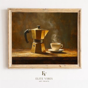 May include: A still life painting shows a gold-coloured stovetop espresso maker and a cup of coffee on a saucer. Steam rises from the cup, suggesting the coffee is hot. The artwork is framed in a light-coloured wooden frame.