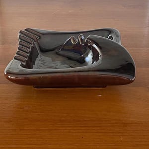 以下が含まれることがあります： 光沢のある濃い茶色の仕上げが施されたヴィンテージ灰皿。セラミック灰皿は、曲線的なデザインと、タバコ用の内蔵レストを備えた長方形の形状をしています。 家庭の装飾のためのクラシックな作品。