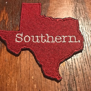 May include: A red felt outline of the state of Texas with the word "Southern" embroidered in white.