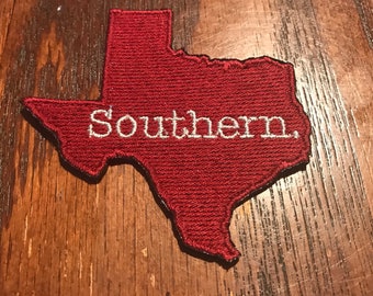 May include: A red felt outline of the state of Texas with the word "Southern" embroidered in white.