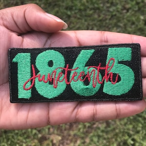 May include: A black fabric patch with green embroidered numbers "1865" and the word "Juneteenth" in red embroidery.