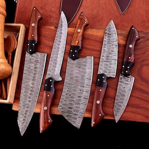 May include: Five kitchen knives with wooden handles and a Damascus steel blade. The knives are arranged on a wooden cutting board.