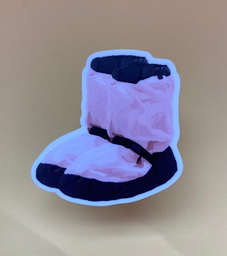 May include: A pink and black fuzzy boot sticker. The boot is puffy and has a black strap across the top.