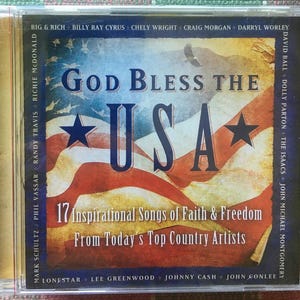 May include: A CD case featuring the text "God Bless the USA" over an American flag design. The CD includes 17 inspirational songs by top country artists. The case is clear with a gold-colored spine.
