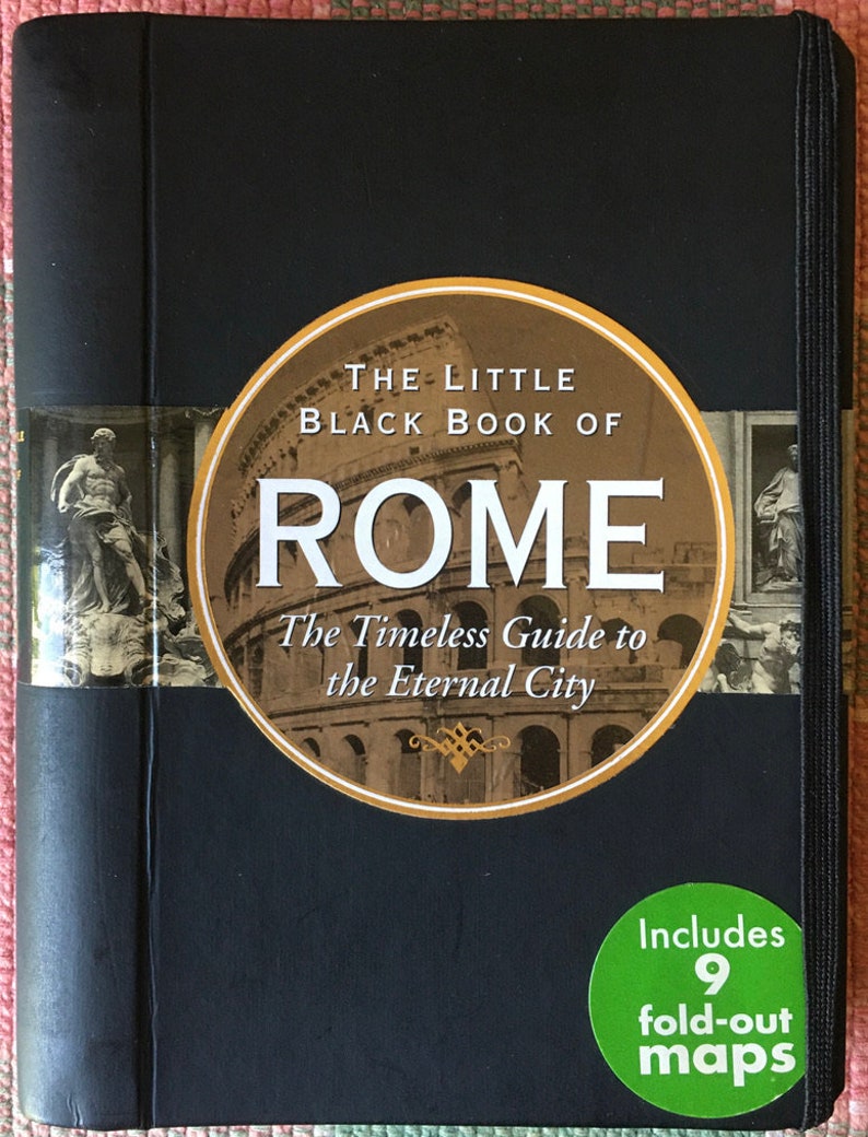 Pu&ograve; includere: Un libro nero rilegato in tela con il titolo "The Little Black Book of Rome: The Timeless Guide to the Eternal City". La copertina presenta un'immagine circolare del Colosseo e un adesivo che dice "Include 9 mappe pieghevoli".