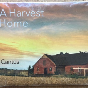 May include: A CD case with the title "A Harvest Home" and the artist name "Cantus" printed on the front. The cover art features a rural landscape with a red brick building, a field of wheat, and a sunset sky.