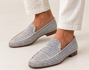 May include: A pair of slip-on loafers featuring a woven texture in alternating blue and cream threads. The shoes have a low-profile silhouette with a rounded toe, a visible stitched seam along the top, and a flat brown sole with a small heel.
