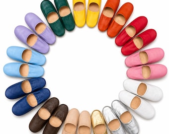 May include: A circular arrangement of leather slippers in various colors including yellow, orange, red, pink, white, silver, gold, beige, brown, dark blue, light blue, purple, and green. Each pair of slippers features a rounded toe and slip-on design.