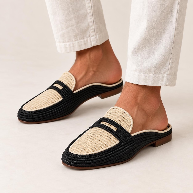 Puede incluir: Un par de mocasines sin tal&oacute;n con textura tejida y dise&ntilde;o bicolor. Los zapatos presentan un borde exterior negro y un panel central beige en el empeine, terminados con un tac&oacute;n bajo de color marr&oacute;n y una puntera redondeada tipo slip-on.