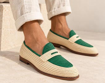 May include: A pair of loafers featuring a woven texture with a cream-colored base and a contrasting dark green panel across the top and collar. The shoes have a low brown heel and a classic penny loafer strap detail across the vamp.