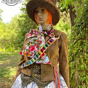 May include: A brown and gold brocade jacket with a colorful butterfly print bow tie and a spool of thread belt. The jacket has a gold and black vest underneath. The person is wearing a white skirt with a black and white print and a tall brown top hat with a red band.