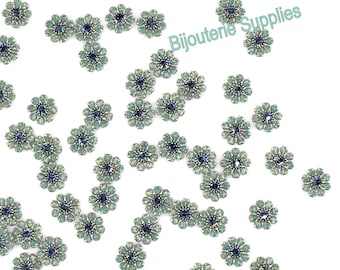 May include: A scattering of teal blue and silver flower-shaped embellishments on a white background.  The embellishments are made of beads and have a sparkly finish.