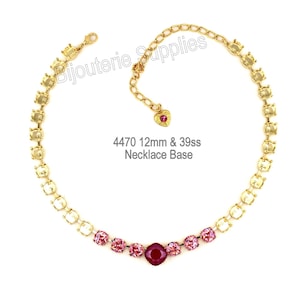 May include: A gold-coloured necklace base with clear and pink gemstones. The necklace has a central, larger, deep red gemstone. The text "4470 12mm & 39ss Necklace Base" is visible.