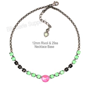 May include: A necklace base with a dark chain and a row of green and black crystals, with a central pink crystal. The text "12mm Rivoli & 29ss Necklace Base" is visible.
