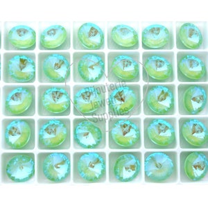 May include: A tray of 36 round, light blue and green iridescent glass rhinestones. The rhinestones are arranged in a grid pattern.