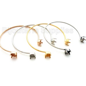 May include: Four silver, gold, rose gold, and black metal bangle bracelets with a round bezel setting for a cabochon.  The bezels are open on the back.