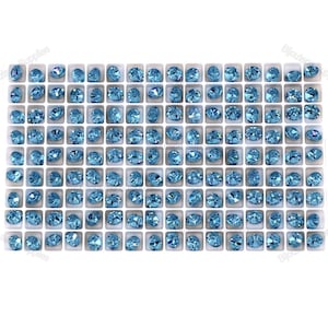May include: A close-up view of a large quantity of light blue rhinestones arranged in a grid pattern. The rhinestones are in individual compartments, creating a uniform and organised display.