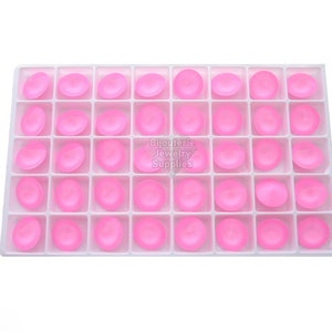 May include: A white plastic tray with 48 pink round cabochons. The tray is divided into 6 rows of 8 compartments.
