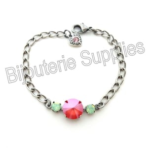 May include: A silver chain bracelet with a pink heart charm and three crystal stones. The centre stone is a large, round, pink crystal. The two smaller stones are round and green.