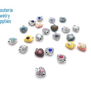 May include: Assortment of silver heart-shaped charms with colorful rhinestones. Each charm features an intricate design and a single rhinestone in the center. The charms are perfect for jewelry making and crafting projects.