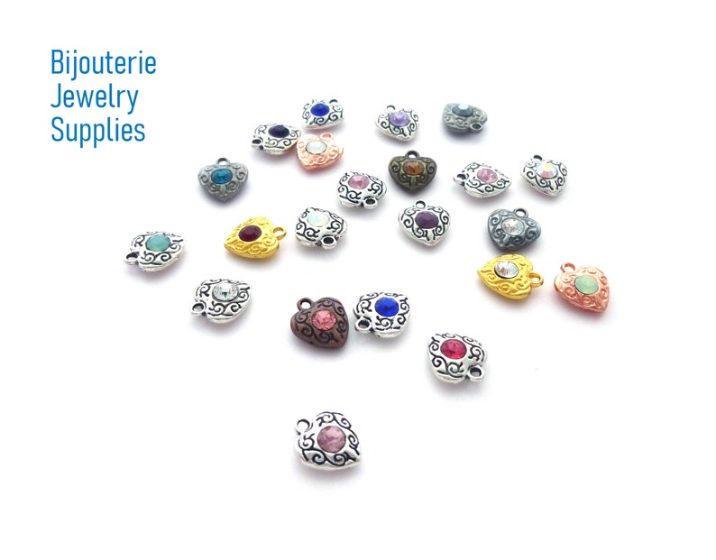 May include: Assortment of silver heart-shaped charms with colorful rhinestones. Each charm features an intricate design and a single rhinestone in the center. The charms are perfect for jewelry making and crafting projects.