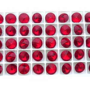 May include: A white plastic tray filled with 36 red round rhinestones. The rhinestones are arranged in a grid pattern.