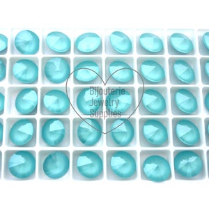 May include: A white tray filled with 36 turquoise round glass rhinestones. The rhinestones are arranged in a grid pattern. The tray is labelled "Bijouterie Jewelry Supplies".
