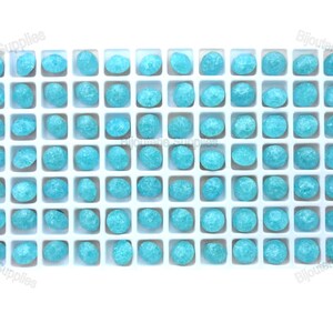May include: A white tray filled with 60 turquoise blue round cabochon gemstones. The gemstones are arranged in a grid pattern.
